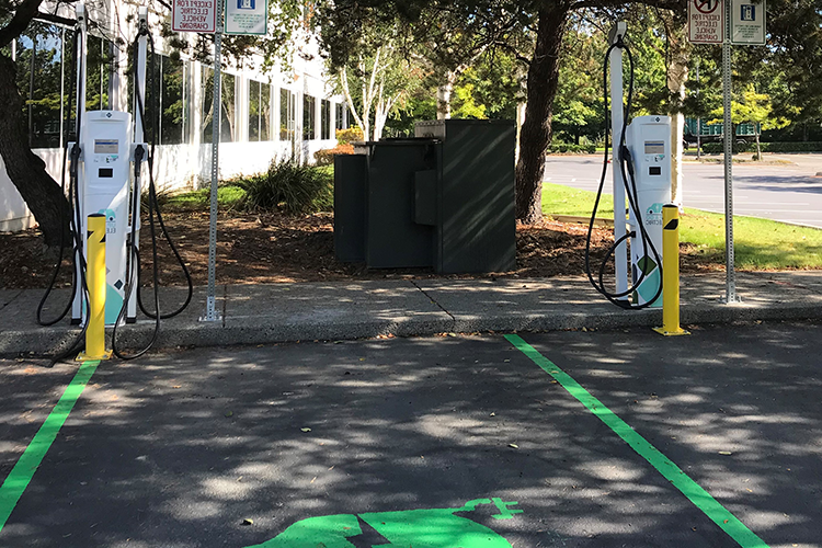 Two shaded parking spaces with PSE branded "Up & Go Electric" charging stations.
